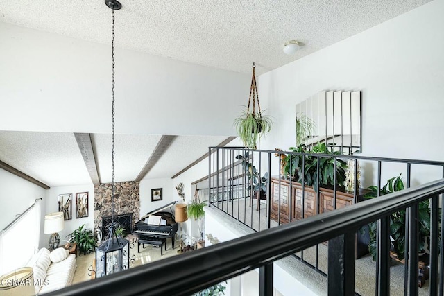 interior details featuring a textured ceiling, beamed ceiling, and a stone fireplace