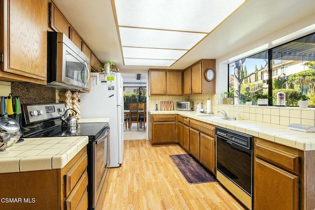 kitchen with a wealth of natural light, tile countertops, and appliances with stainless steel finishes