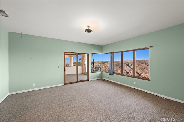 unfurnished room with a wealth of natural light, carpet floors, and a mountain view