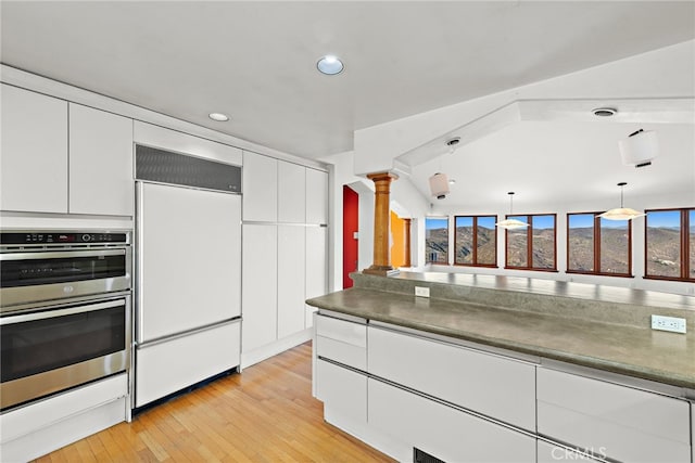 kitchen featuring white cabinets, ornate columns, stainless steel double oven, paneled refrigerator, and pendant lighting