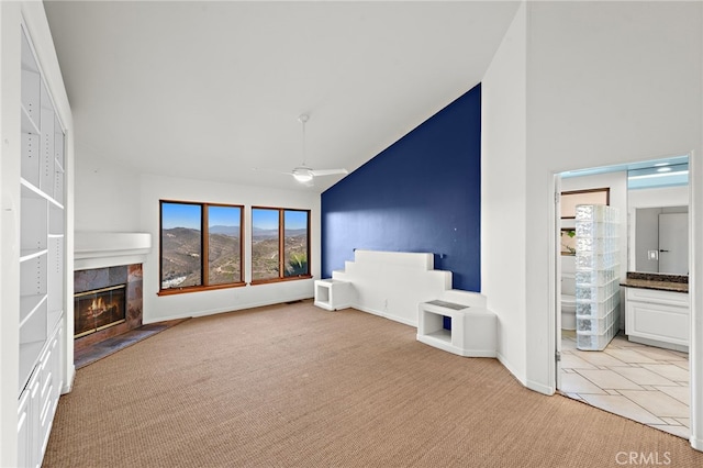 unfurnished living room with a tile fireplace, ceiling fan, vaulted ceiling, and light tile patterned floors