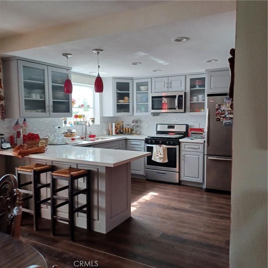 kitchen featuring kitchen peninsula, tasteful backsplash, gray cabinetry, appliances with stainless steel finishes, and sink