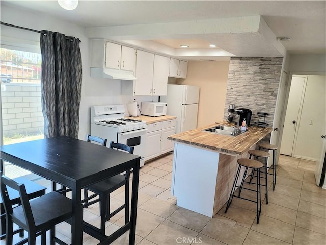 kitchen with white appliances, white cabinetry, sink, a kitchen breakfast bar, and light tile patterned floors