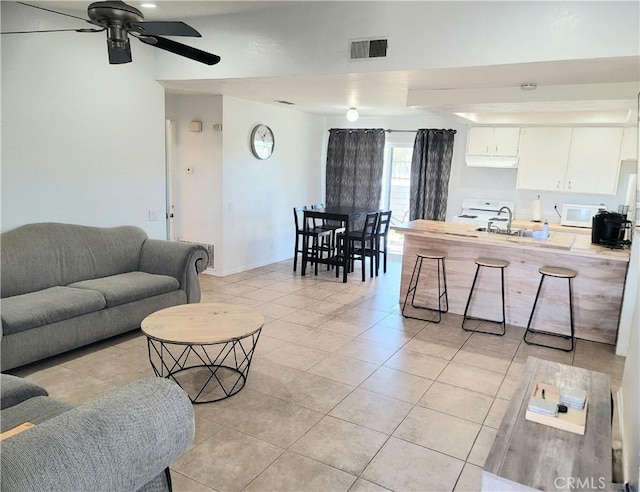 tiled living room featuring ceiling fan and sink