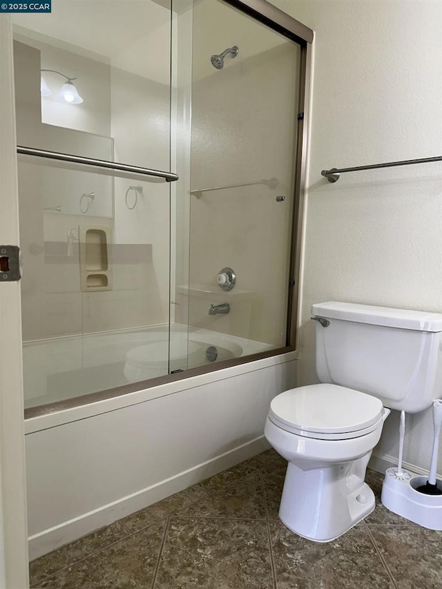 bathroom with toilet and bath / shower combo with glass door