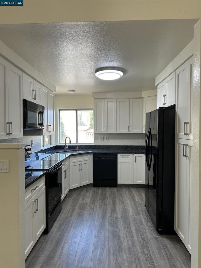 kitchen featuring dark wood-type flooring, a textured ceiling, black appliances, white cabinetry, and sink