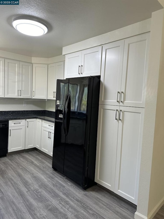 kitchen featuring a textured ceiling, white cabinetry, hardwood / wood-style floors, and black appliances