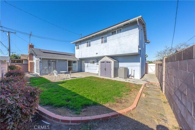 back of house with a lawn, solar panels, a storage unit, a patio, and central air condition unit