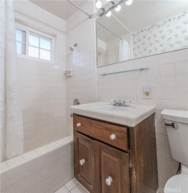 full bathroom with toilet, tile patterned flooring, tile walls, shower / bathtub combination with curtain, and vanity