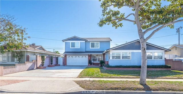 traditional-style house featuring concrete driveway, fence, a garage, and a front yard