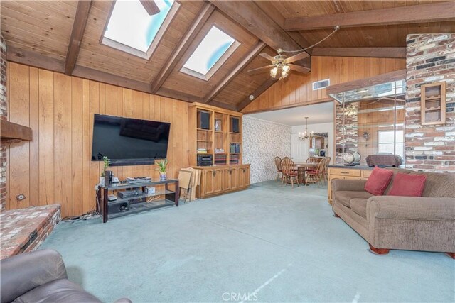 living room with wooden walls, carpet flooring, ceiling fan with notable chandelier, vaulted ceiling with skylight, and wood ceiling