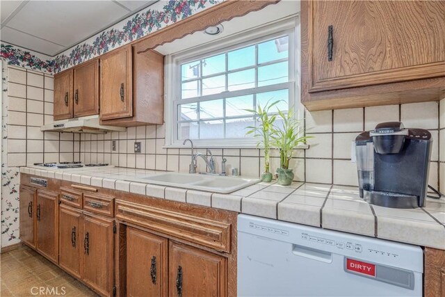 kitchen with white appliances, tile counters, tasteful backsplash, and sink