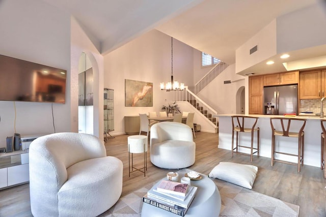 living room featuring light hardwood / wood-style flooring, an inviting chandelier, and a towering ceiling