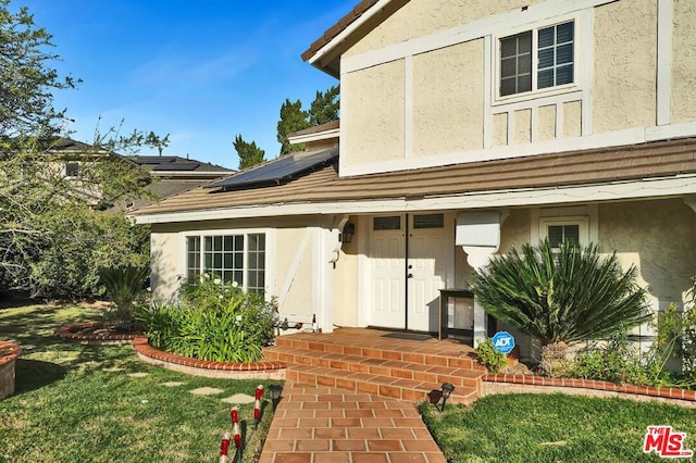 view of exterior entry with a yard and solar panels