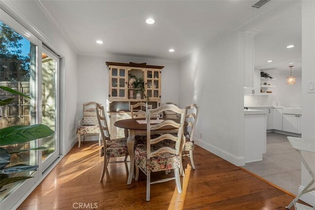 dining area with light hardwood / wood-style flooring and crown molding