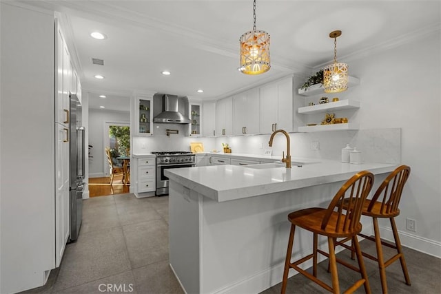 kitchen with white cabinets, wall chimney range hood, kitchen peninsula, and high quality appliances