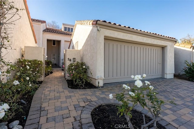 view of front of home featuring a tile roof, an attached garage, and stucco siding