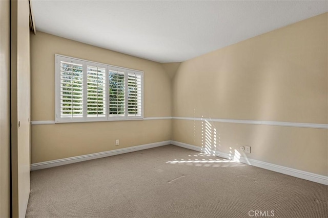 carpeted spare room featuring baseboards