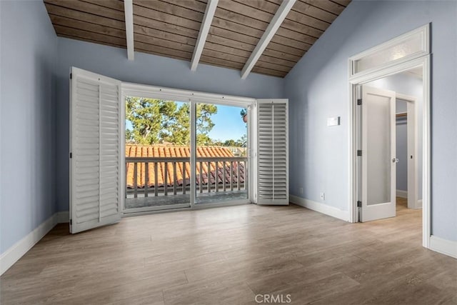 spare room with lofted ceiling with beams, wood ceiling, baseboards, and wood finished floors