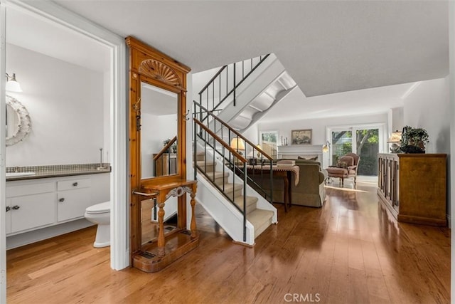 stairway with a fireplace and wood finished floors