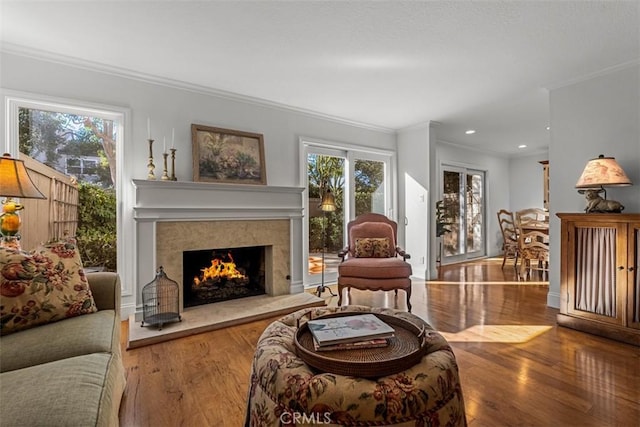 living room with ornamental molding, a high end fireplace, and wood-type flooring