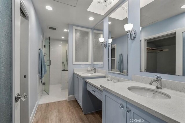 bathroom featuring vanity, a shower with door, hardwood / wood-style floors, and a skylight