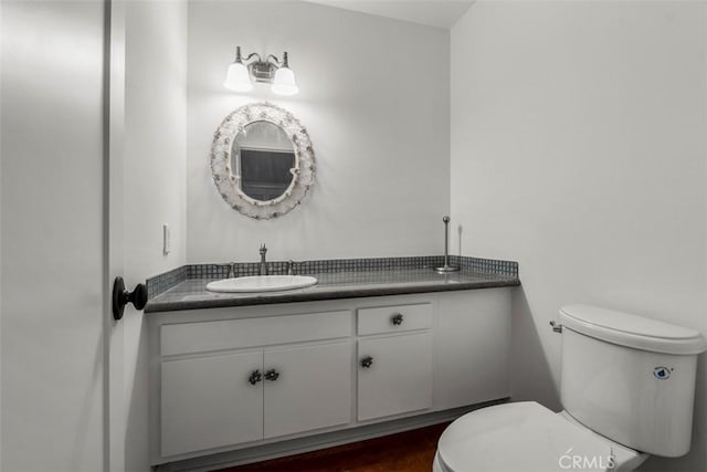 half bathroom featuring toilet, wood finished floors, and vanity