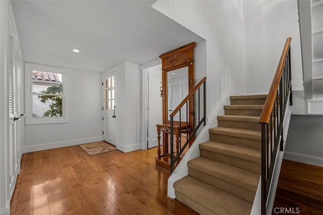 foyer entrance featuring light wood finished floors, stairs, and baseboards