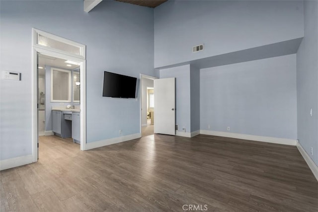 interior space with a towering ceiling, hardwood / wood-style floors, and beamed ceiling