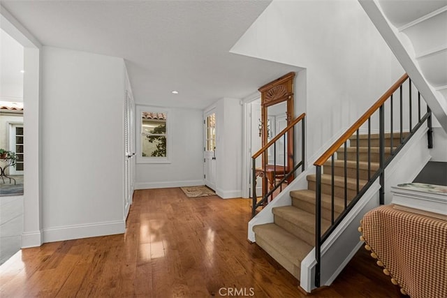 foyer entrance featuring stairs, baseboards, and wood finished floors