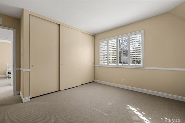 unfurnished bedroom featuring baseboards, a closet, and carpet flooring