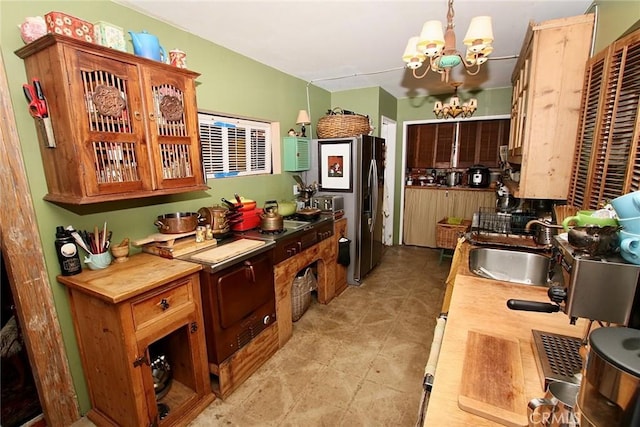 kitchen featuring stainless steel fridge with ice dispenser, a chandelier, pendant lighting, and sink