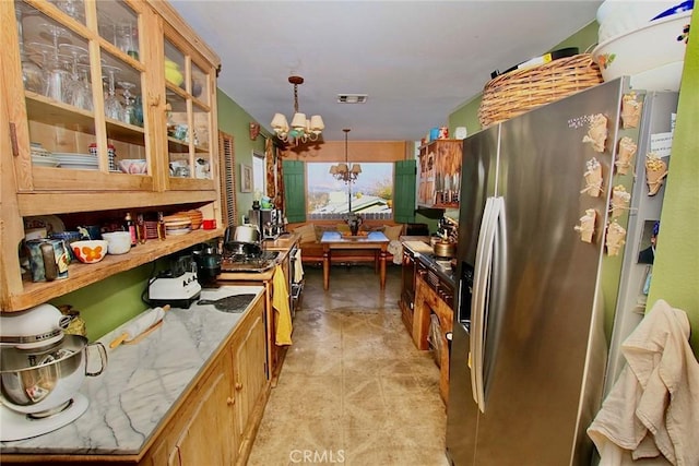 kitchen with light stone counters, pendant lighting, stainless steel fridge with ice dispenser, and an inviting chandelier