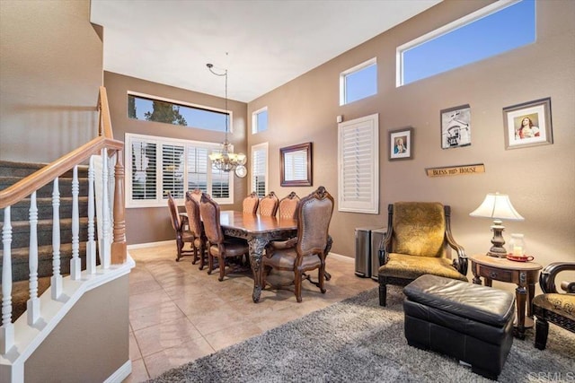 dining space featuring a towering ceiling, an inviting chandelier, and light tile patterned floors