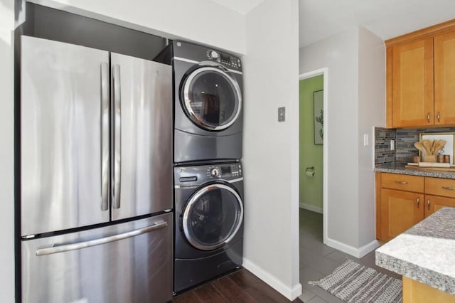 washroom with stacked washer and clothes dryer and dark wood-type flooring