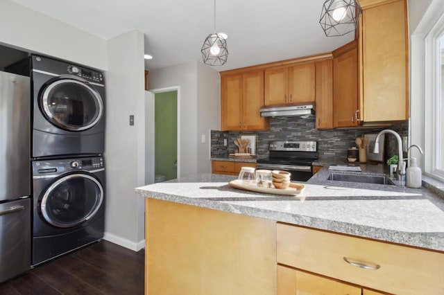 kitchen with dark hardwood / wood-style floors, hanging light fixtures, stainless steel appliances, stacked washer / drying machine, and sink