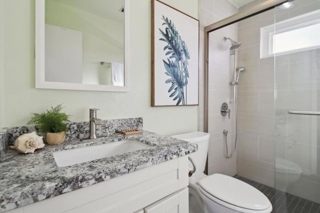 bathroom featuring toilet, a shower with door, and vanity