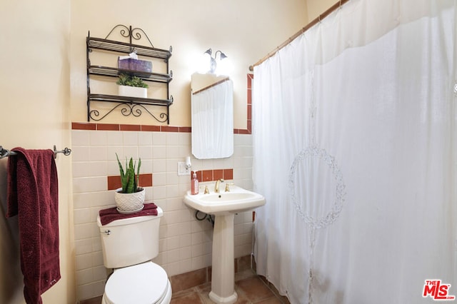 bathroom featuring tile patterned floors, sink, tile walls, and toilet