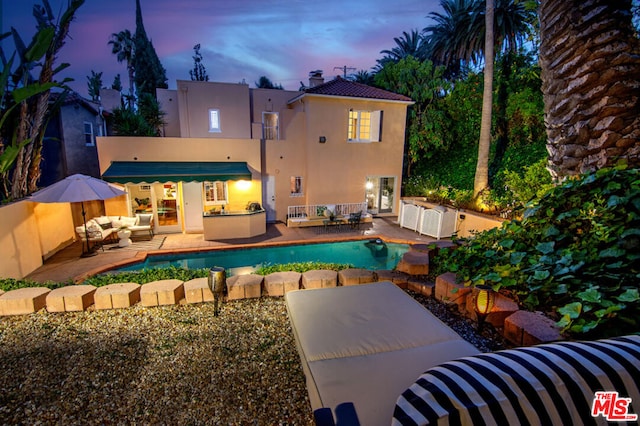 pool at dusk featuring a patio area, an outdoor living space, and area for grilling