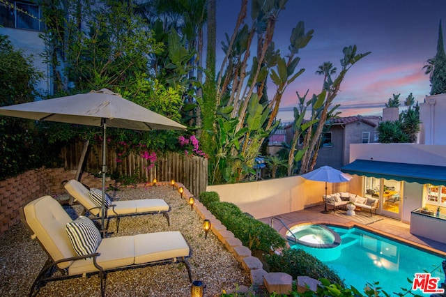 pool at dusk with a patio area and an outdoor hangout area