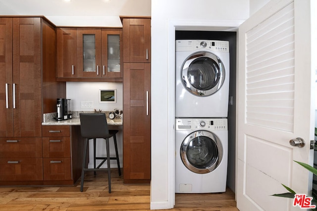 clothes washing area featuring stacked washer / dryer and light hardwood / wood-style flooring