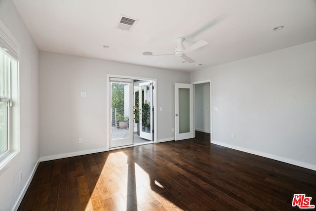 empty room with french doors, a wealth of natural light, and dark hardwood / wood-style floors