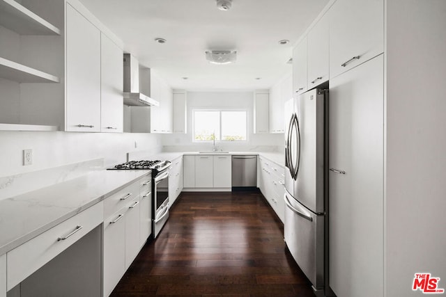 kitchen with wall chimney exhaust hood, dark hardwood / wood-style flooring, white cabinetry, appliances with stainless steel finishes, and sink