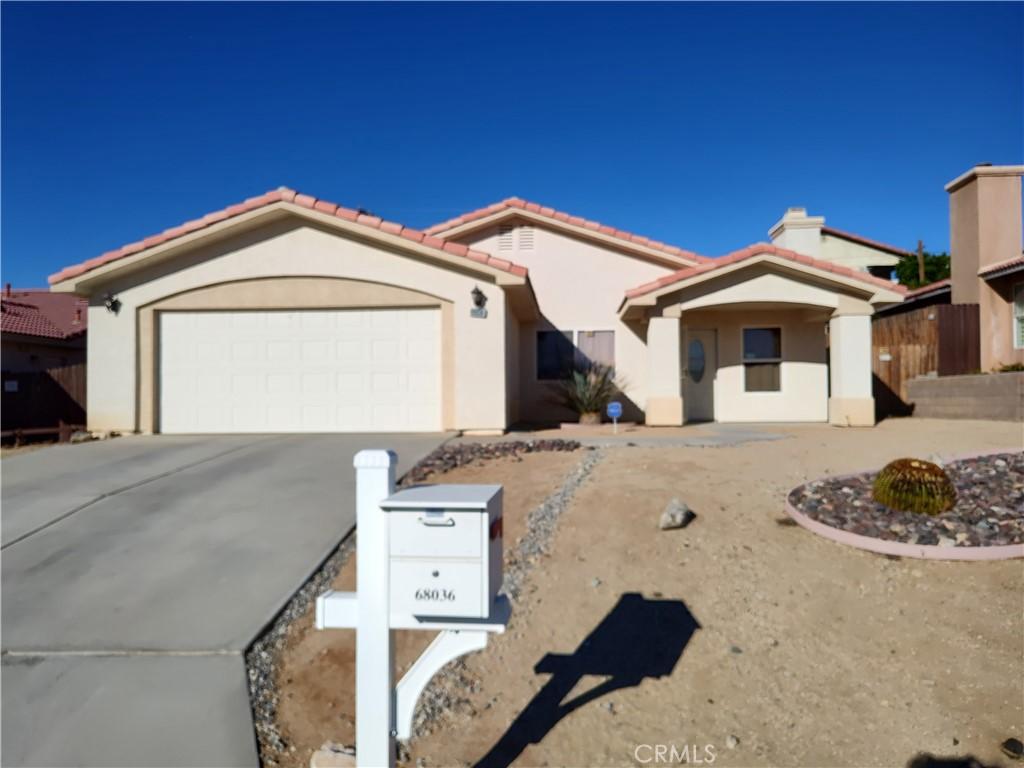 view of front of home with a tiled roof, a garage, driveway, and stucco siding