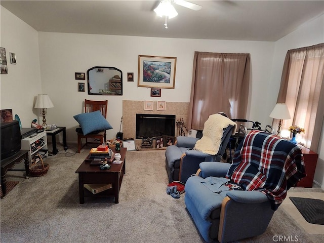 carpeted living room featuring ceiling fan and a tiled fireplace