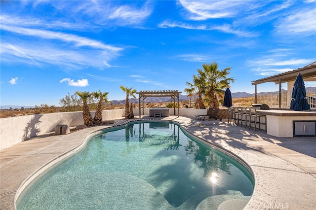 view of swimming pool featuring a mountain view, a bar, a patio, a grill, and a pergola