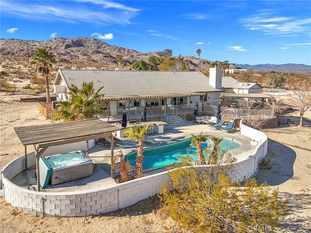 view of pool featuring a mountain view, a patio area, and a hot tub