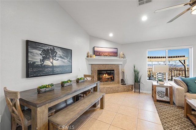 interior space with a tile fireplace, lofted ceiling, ceiling fan, and light tile patterned floors