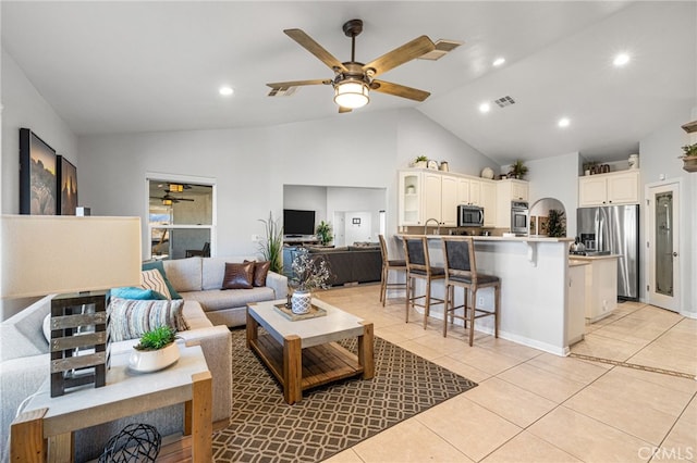 tiled living room with ceiling fan and high vaulted ceiling