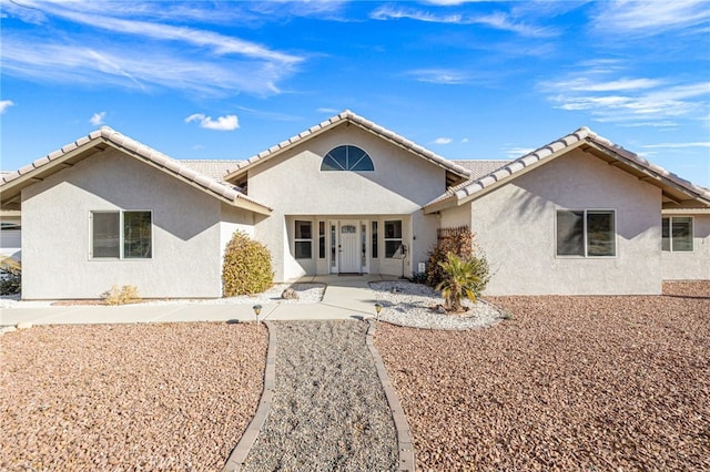 ranch-style house featuring a tiled roof and stucco siding